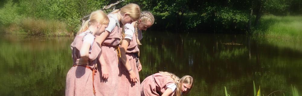 Elever i jernalderdragter henter vand i sø