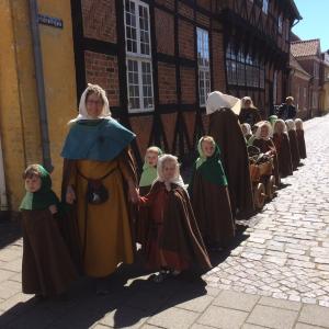 Børn i middelalderdragter på tur med formidler